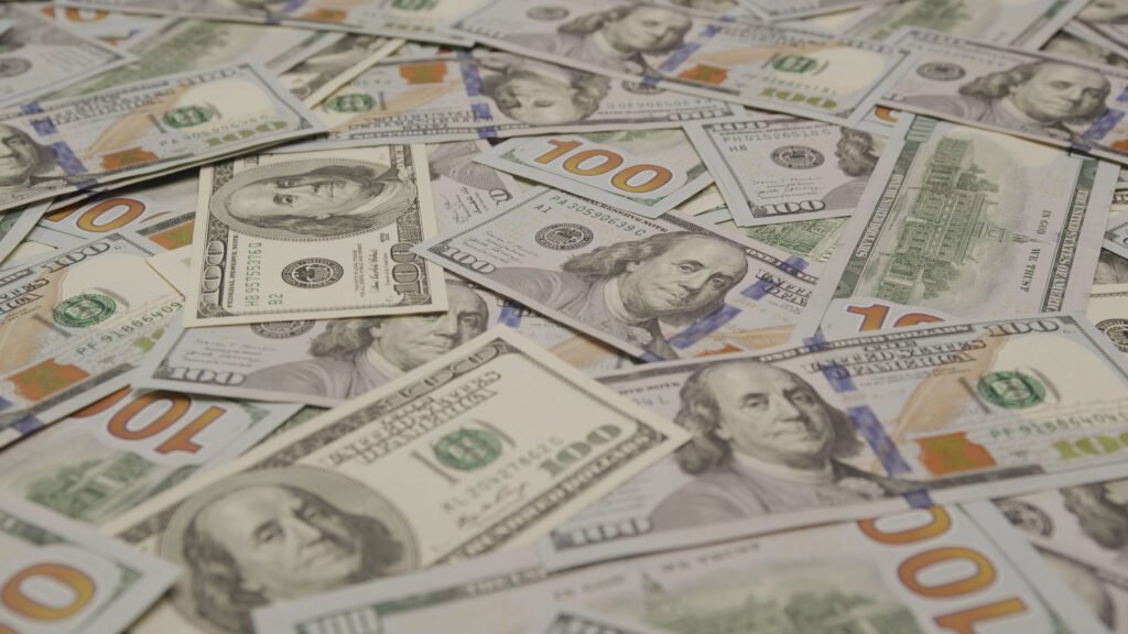 scattered-hundred-dollar-bills-on-desk