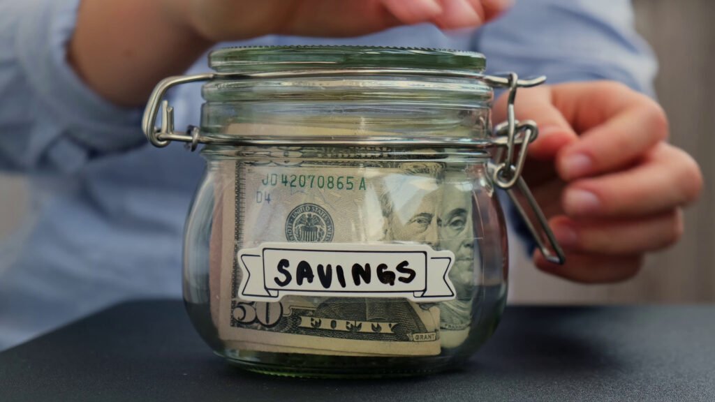 unrecognizable-woman-add-money-to-saving-money-in-jar-filled-with-dollars-banknotes